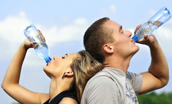 Une femme et un homme qui boivent de l'eau après l'effort.
